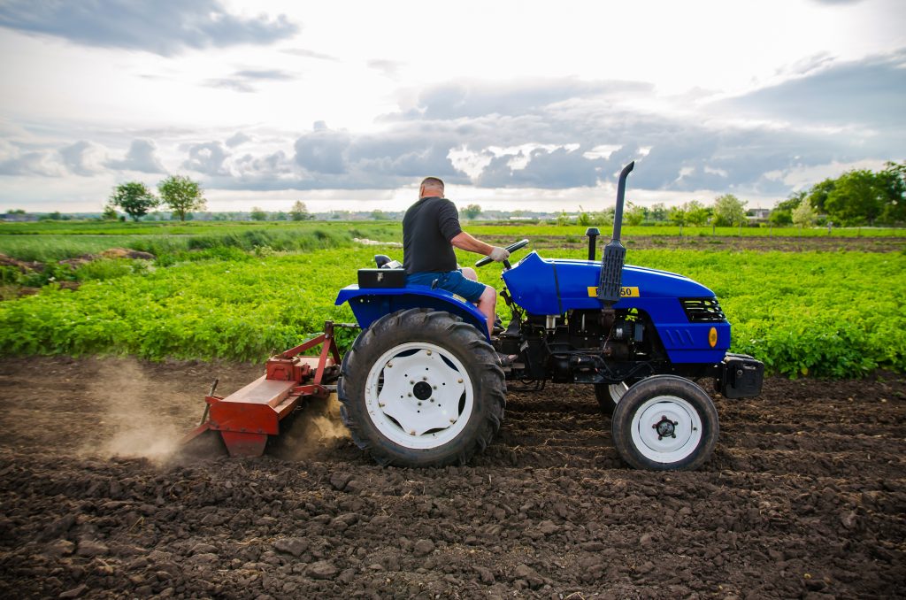 Kherson oblast, Ukraine - May 29, 2021: Farmer on a tractor cleans the field after harvest. Running a small agribusiness. Farm work. Farming. Loosening, land cultivation. Mechanization in agriculture.