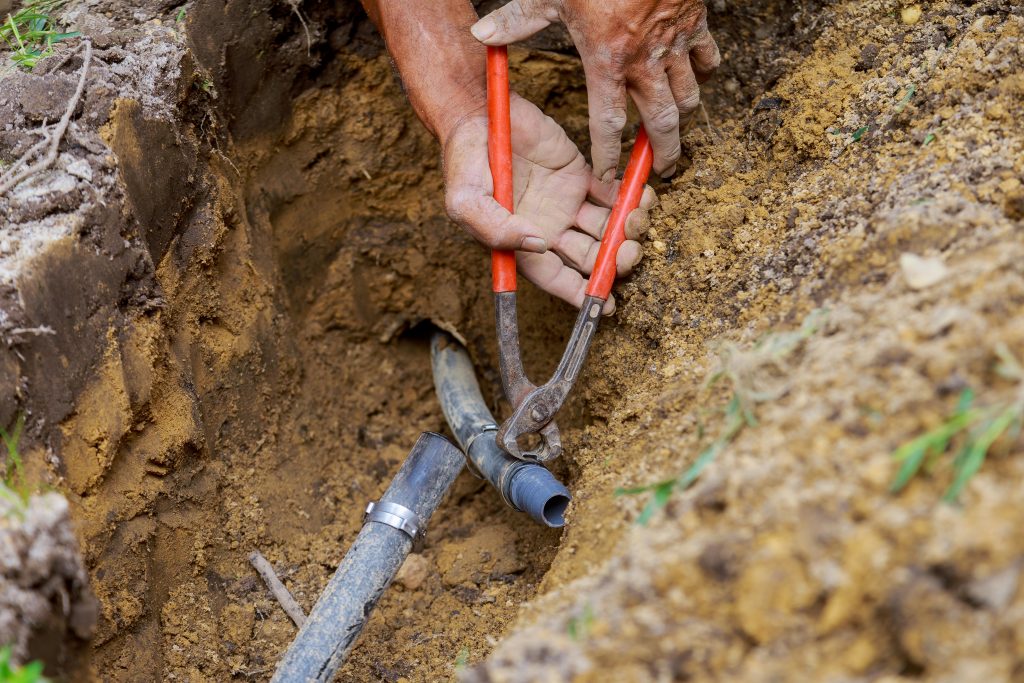 Underground sprinkler system to water the ground in man working with pipes in ground while installing