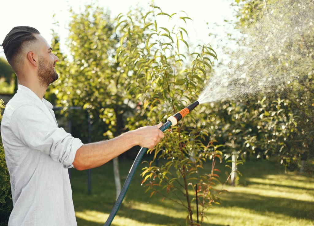 Man in white long sleeve shirt holding gray hose