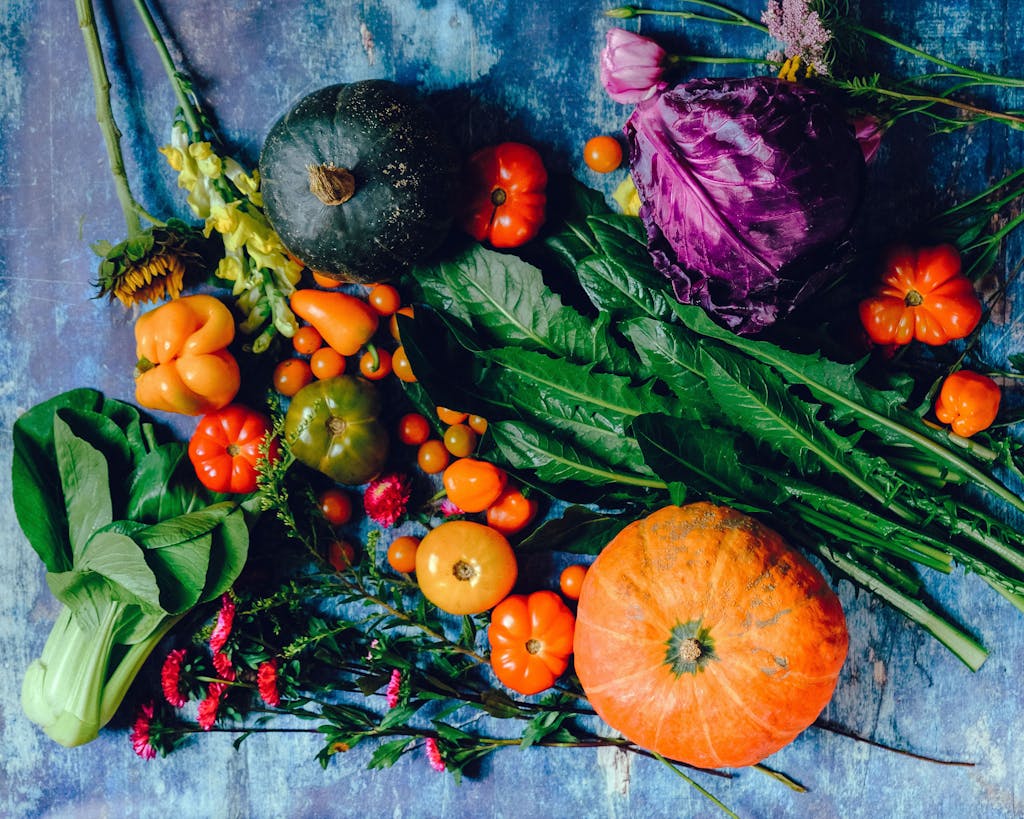 A vibrant assortment of fresh vegetables including pumpkins, cabbage, and tomatoes on a rustic surface.