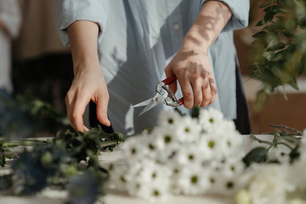 Florist arranging a floral bouquet with scissors on a sunny day.