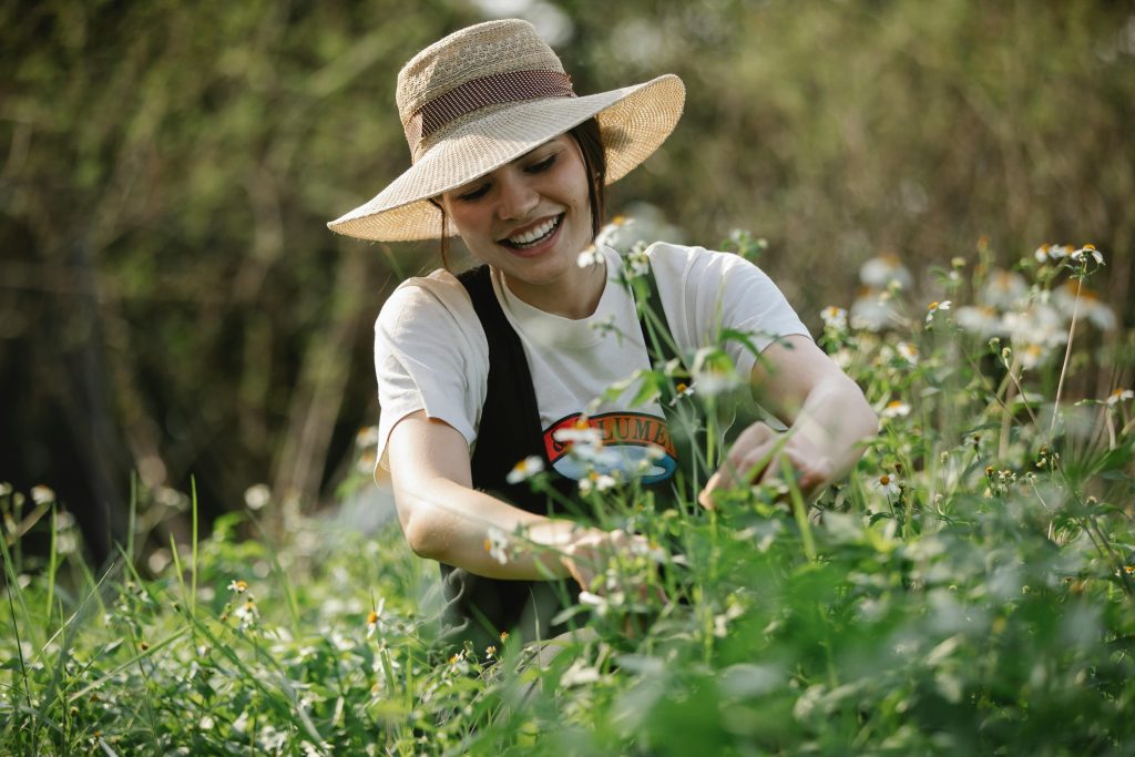 Happy woman in hat near flowers