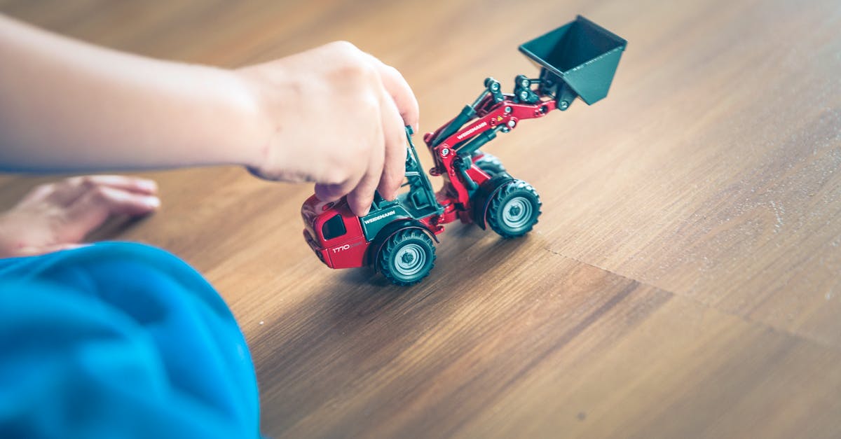 a child plays with a toy excavator on a wooden floor enjoying creative indoor playtime