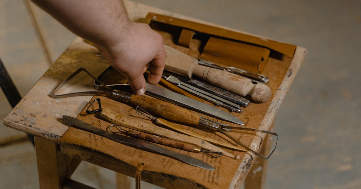 a close up of artisan hand selecting tools on a wooden stool for woodwork 1