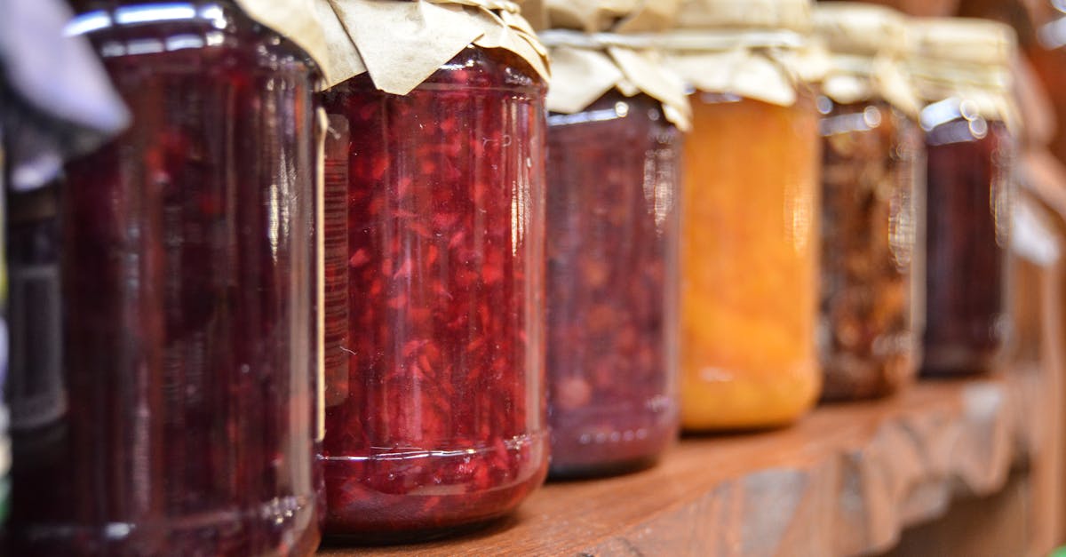 a close up view of various homemade jam jars lined up on a wooden shelf