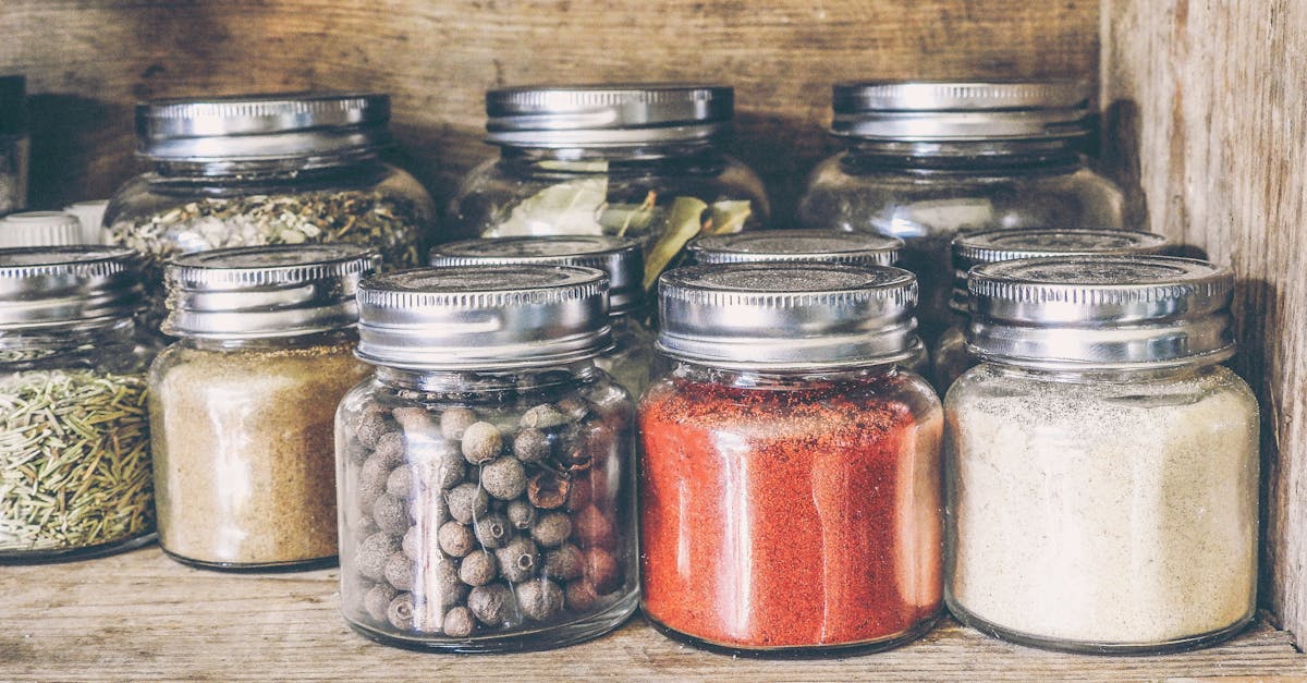 a collection of assorted spices in glass jars on a rustic wooden shelf for culinary use