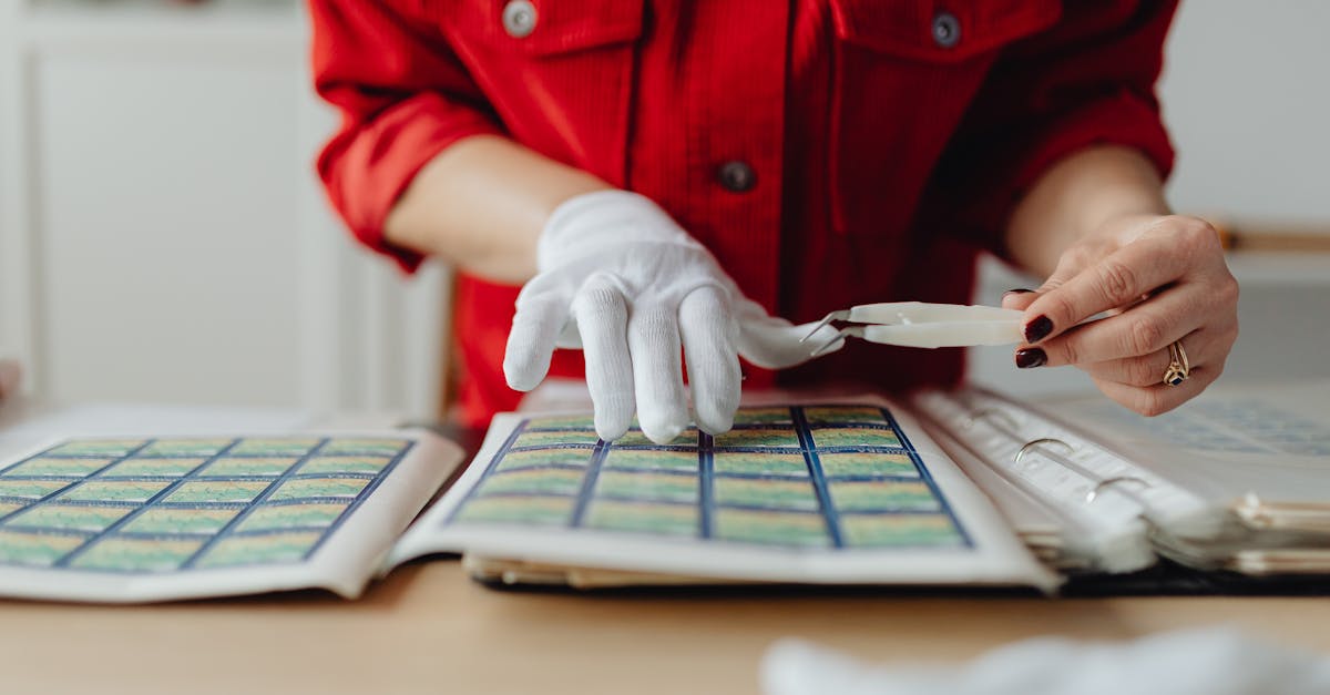 a collector carefully arranges postage stamps using tweezers and gloves indoors