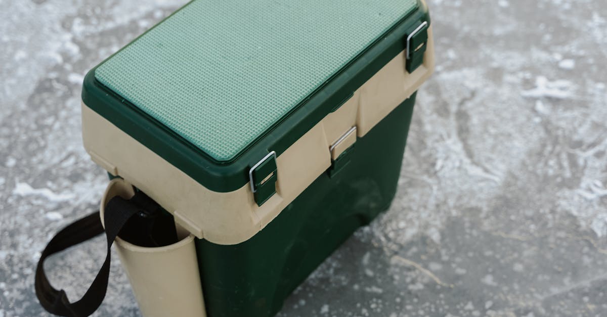 a green and beige cooler sits on a frozen ice surface ideal for outdoor adventures