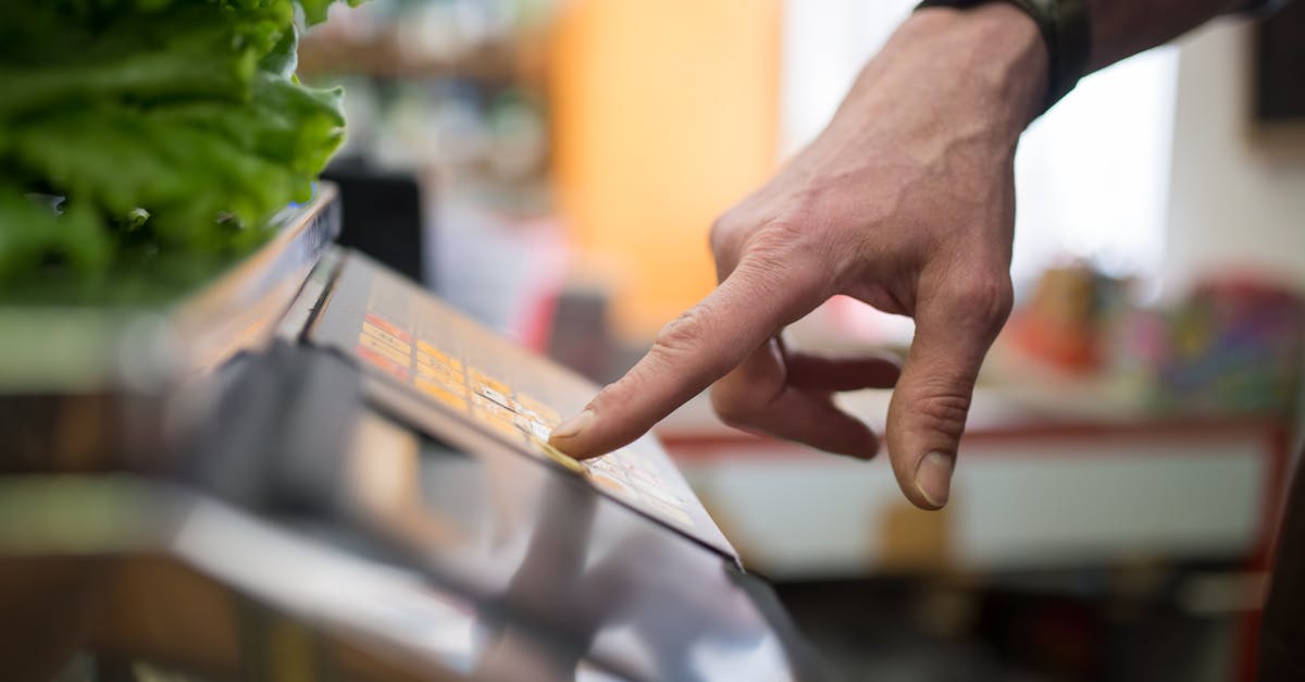 a hand interacting with a digital weighing scale in a produce section emphasizing technology in sho