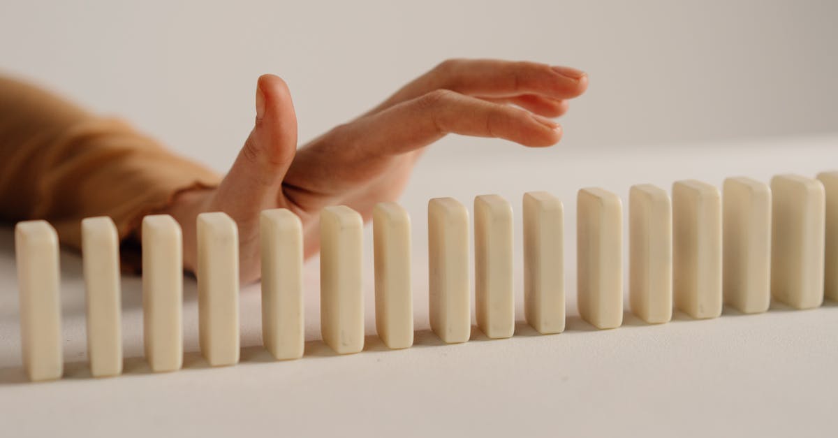 a hand poised to stop falling dominoes depicting control and intervention