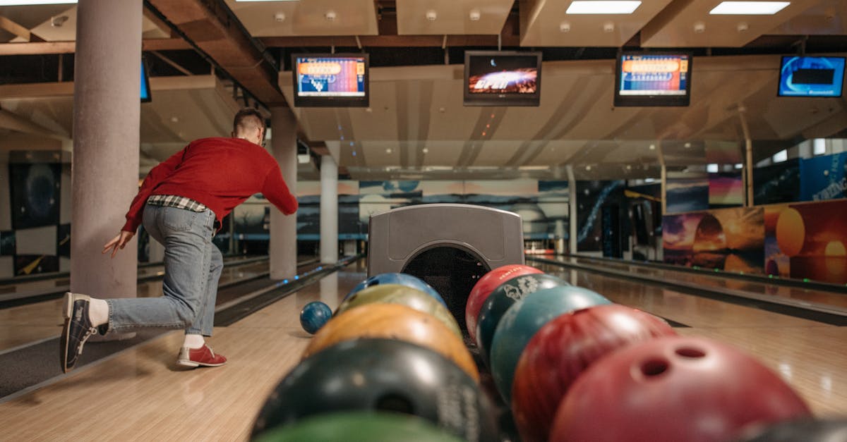 a man in a bowling alley throwing a bowling ball down a lane with colorful balls in the foreground