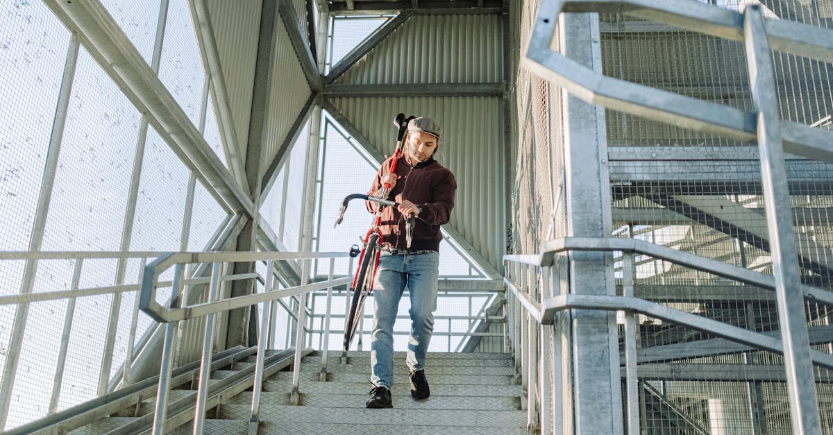 a man steps down metal stairs carrying a bicycle captured in a modern architectural setting