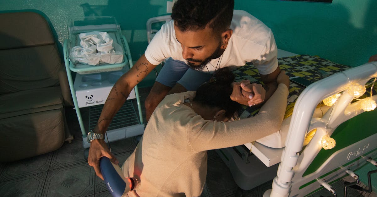 a man supports a woman in labor at a hospital bedside holding her hand and using a device for comfo