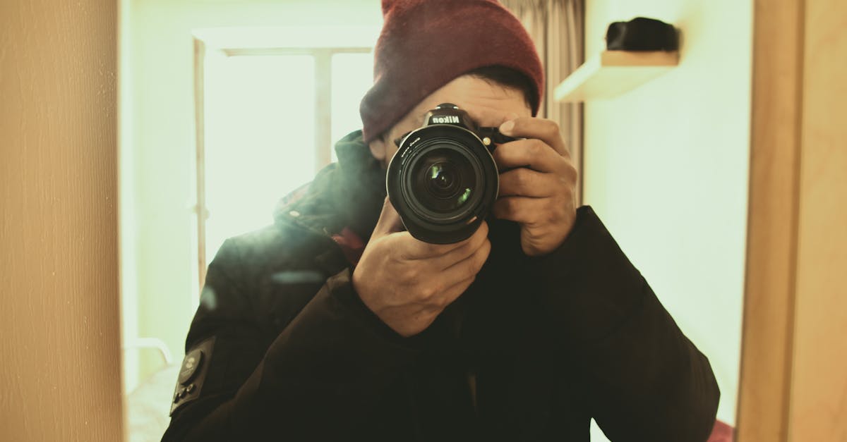 a man with a nikon camera capturing a self portrait indoors in warm lighting