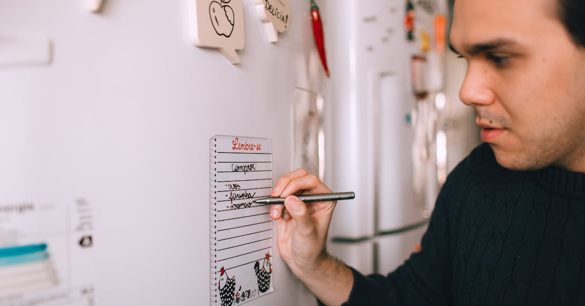 a man writes a reminder note on a refrigerator notepad to stay organized at home