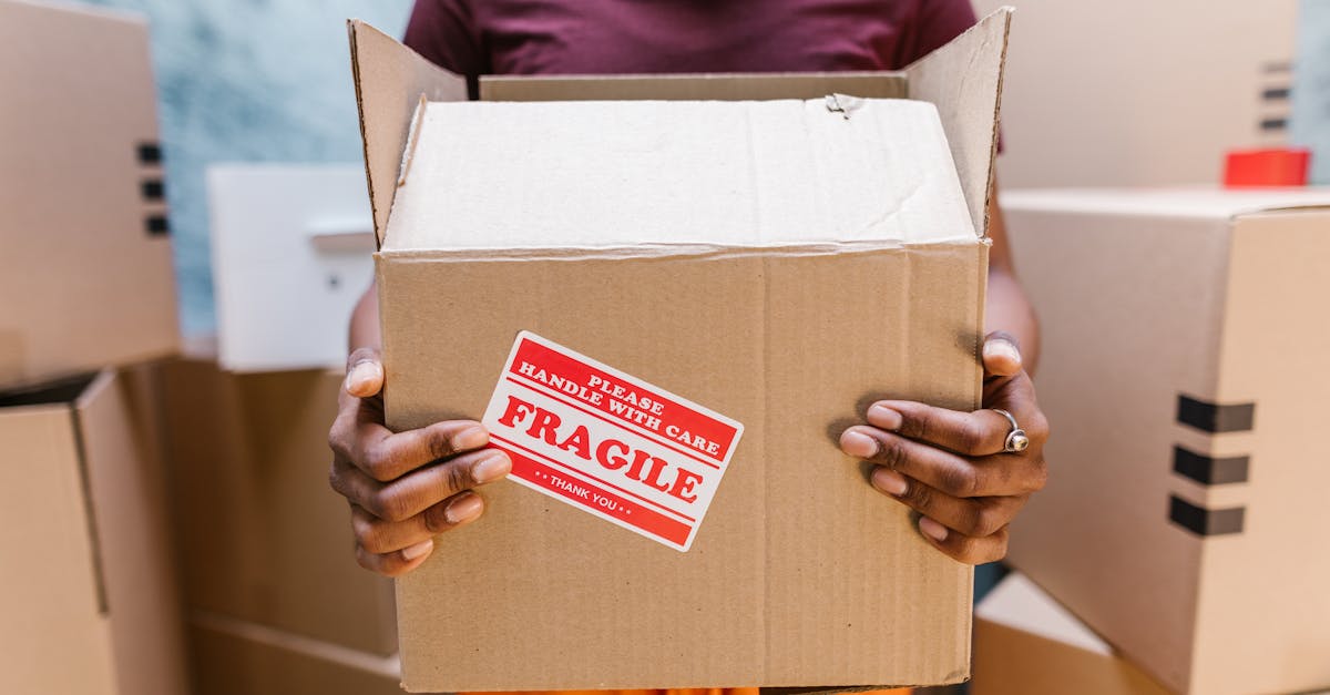 a person holding a cardboard box labeled fragile during a moving process indoors