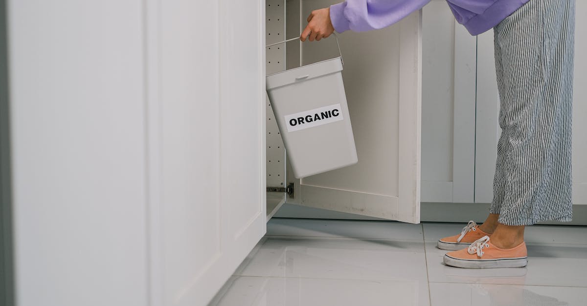 a person placing an organic waste bin inside a modern kitchen cabinet promoting sustainable living