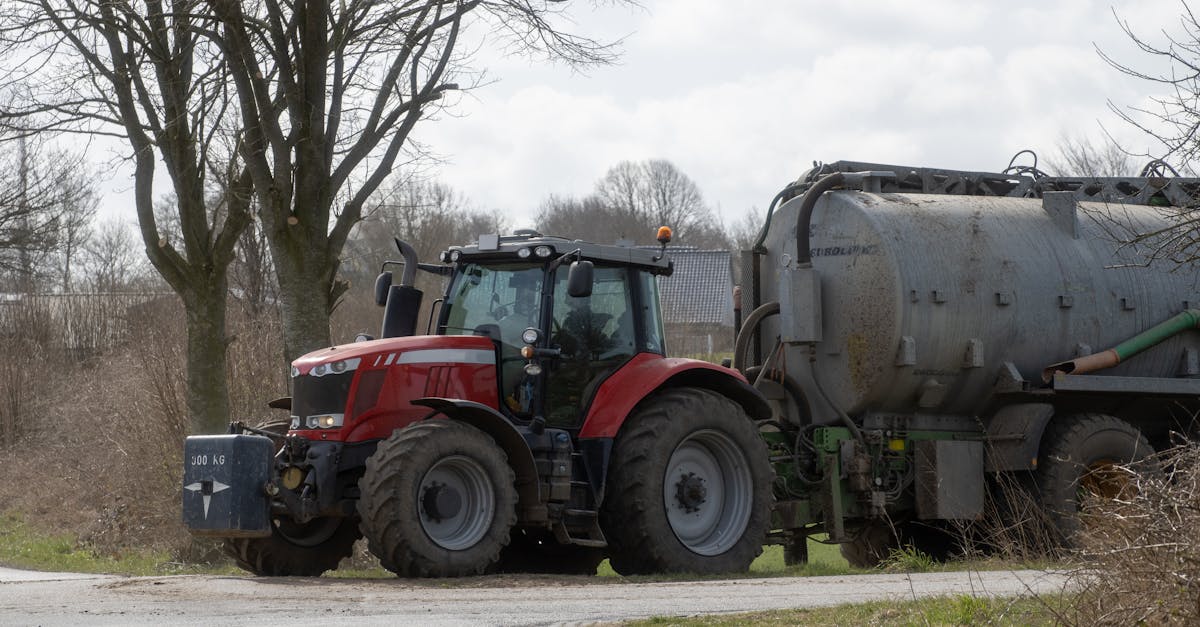 a red tractor with a manure spreader parked on a farm road in springtime rural landscape