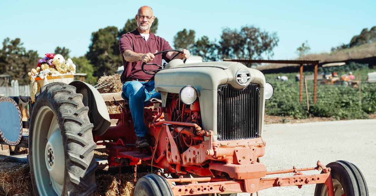 a smiling bald man drives a vintage tractor on a sunny farm day surrounded by summer scenery 1