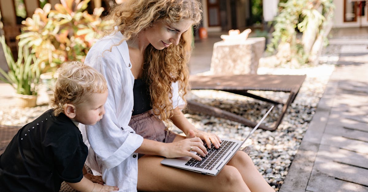 a woman and young boy enjoy a sunny day outdoors while using a laptop