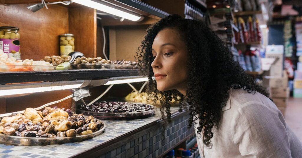 a woman examining a selection of olives in a gourmet food store with a variety of options