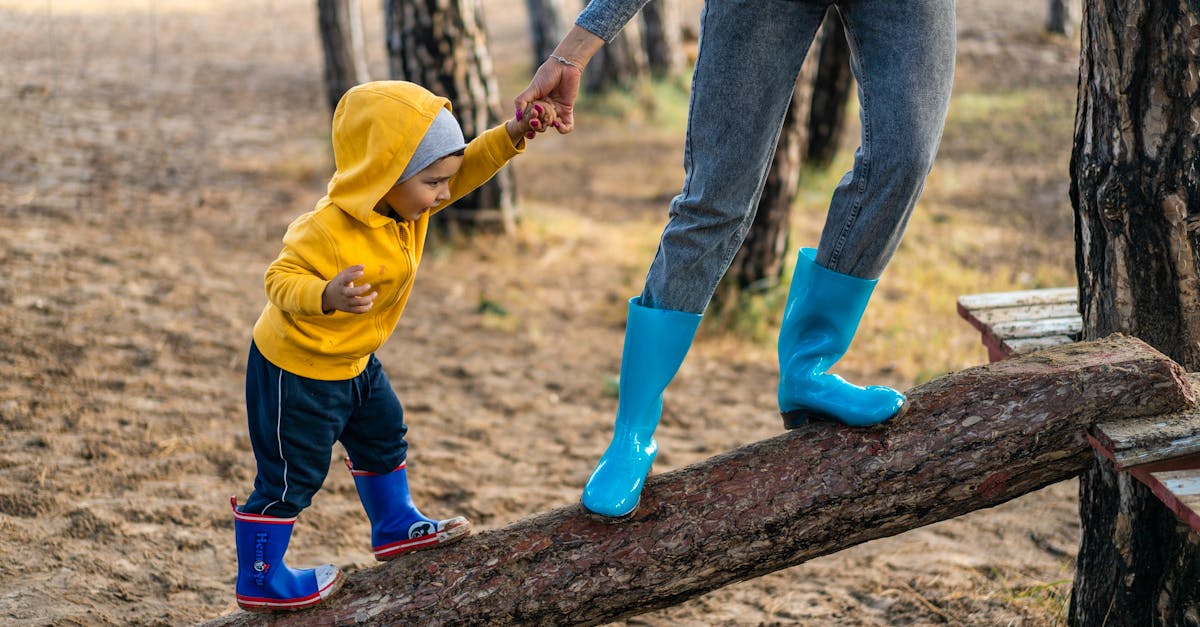 a woman helps her toddler walk on a log in a park showcasing child support and family bonding