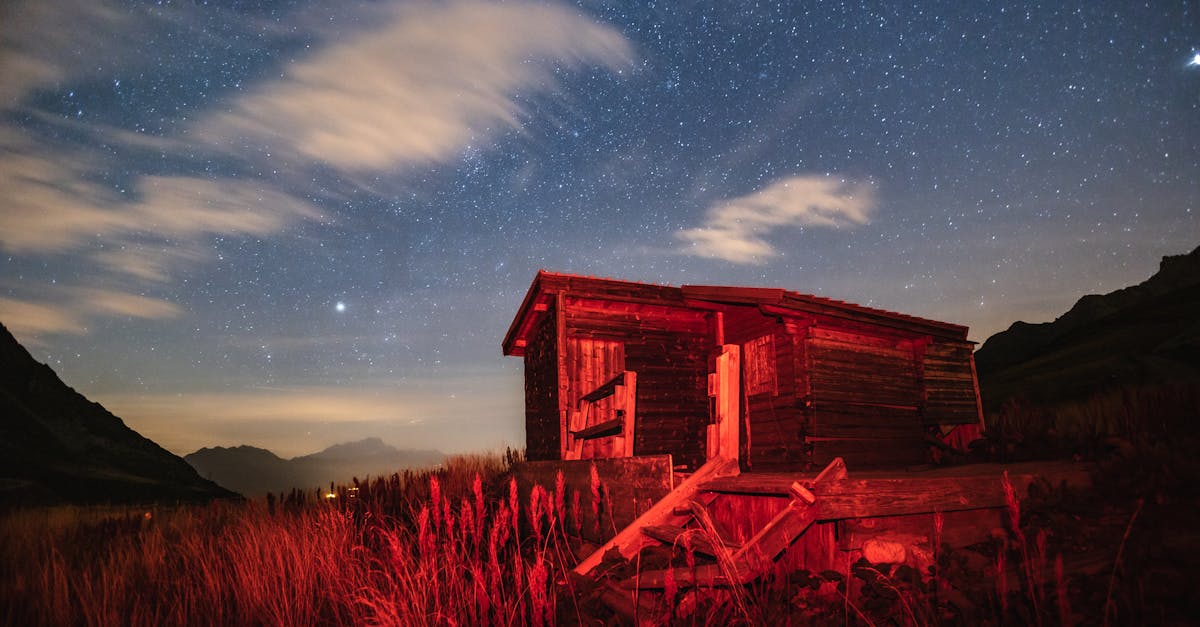 a wooden cabin illuminated by red light under a starry night sky in a rural landscape 1