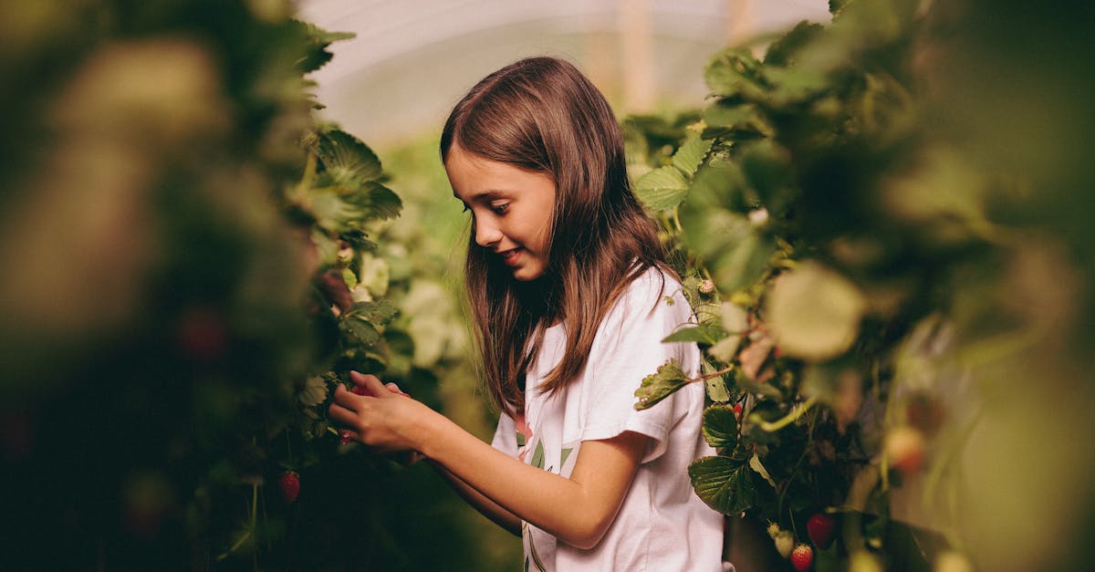 a young girl smiles joyfully as she touches plants in a vibrant greenhouse