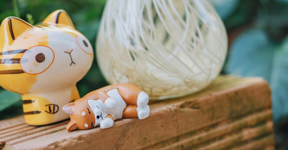 adorable ceramic cat figurines placed on a rustic brick surface with a blurred green background