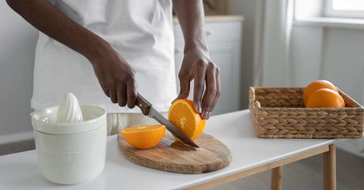 an adult slicing fresh oranges on a wooden chopping board in a bright kitchen setting