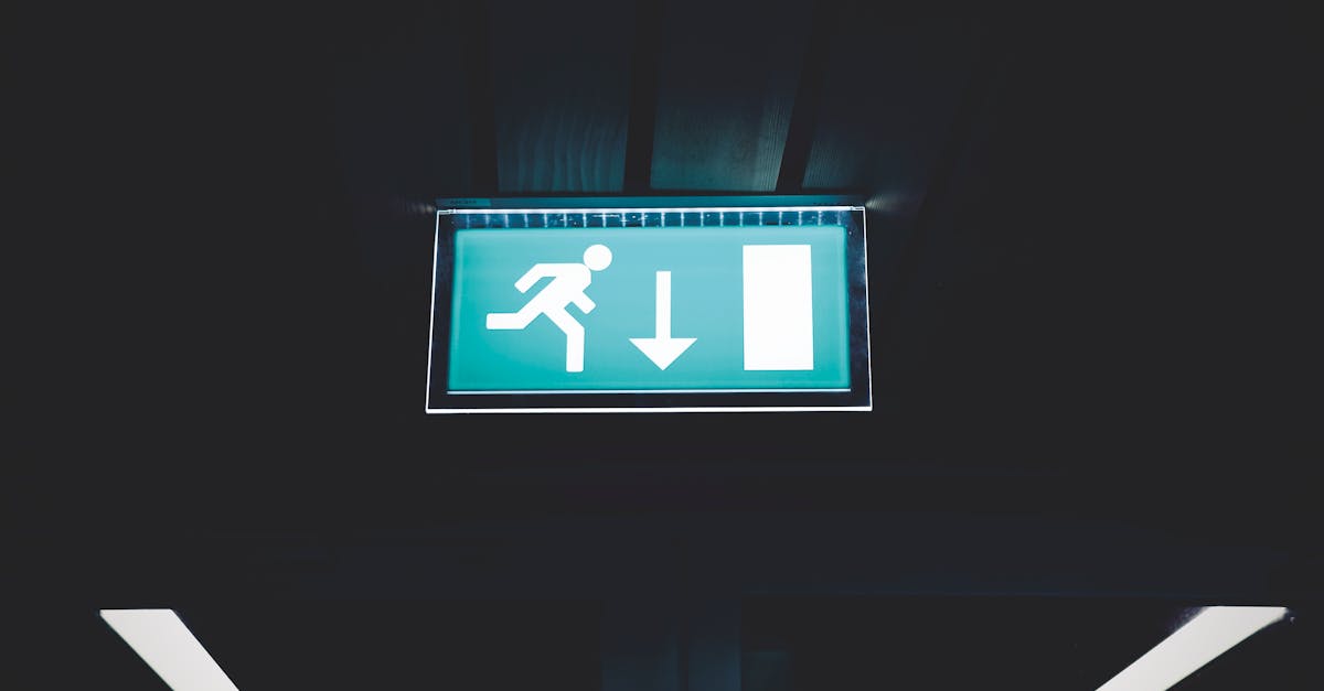 brightly lit emergency exit sign with arrow indicating direction set against a dark backdrop