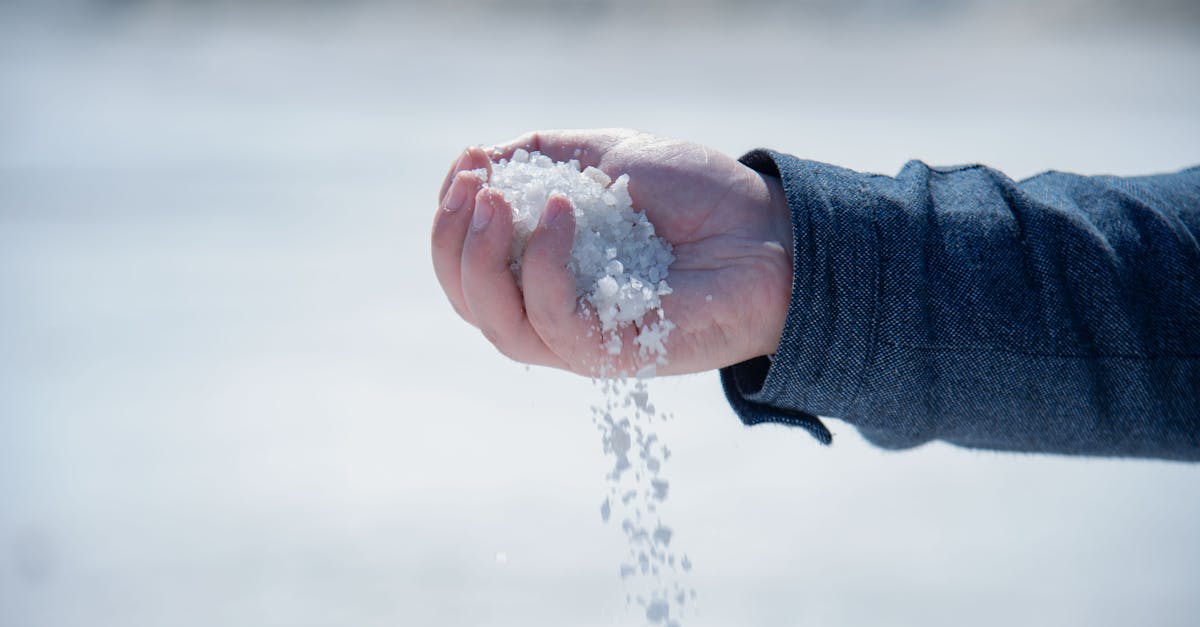 close up of a hand holding and pouring coarse white salt outdoors