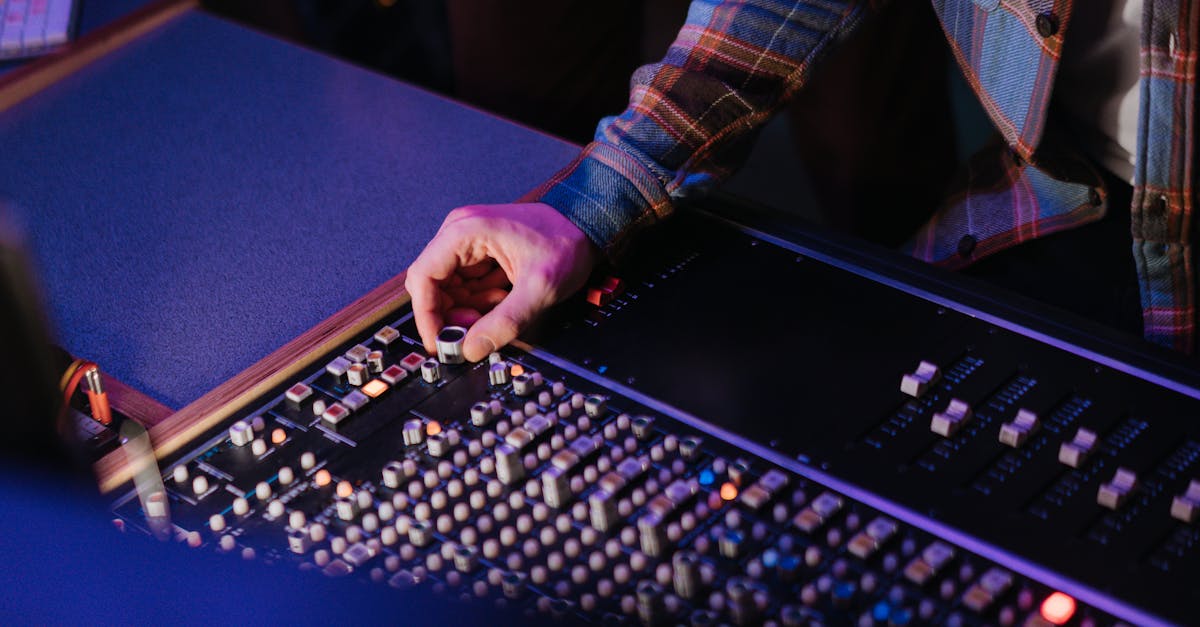 close up of a person adjusting a mixing console in a dimly lit music studio