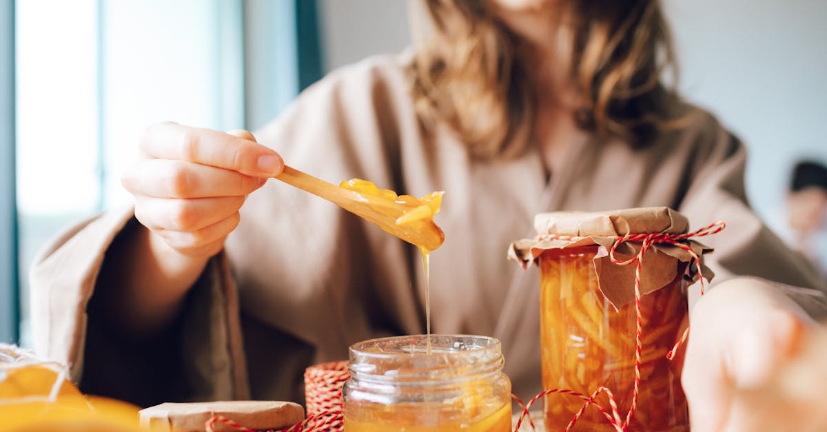 close up of a woman preparing fresh orange marmalade in glass jars capturing the essence of homemad