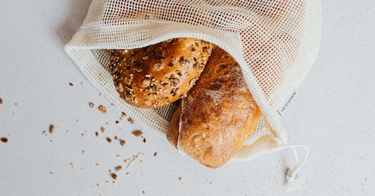 close up of artisan bread in a reusable mesh bag on a white surface showcasing zero waste lifestyle