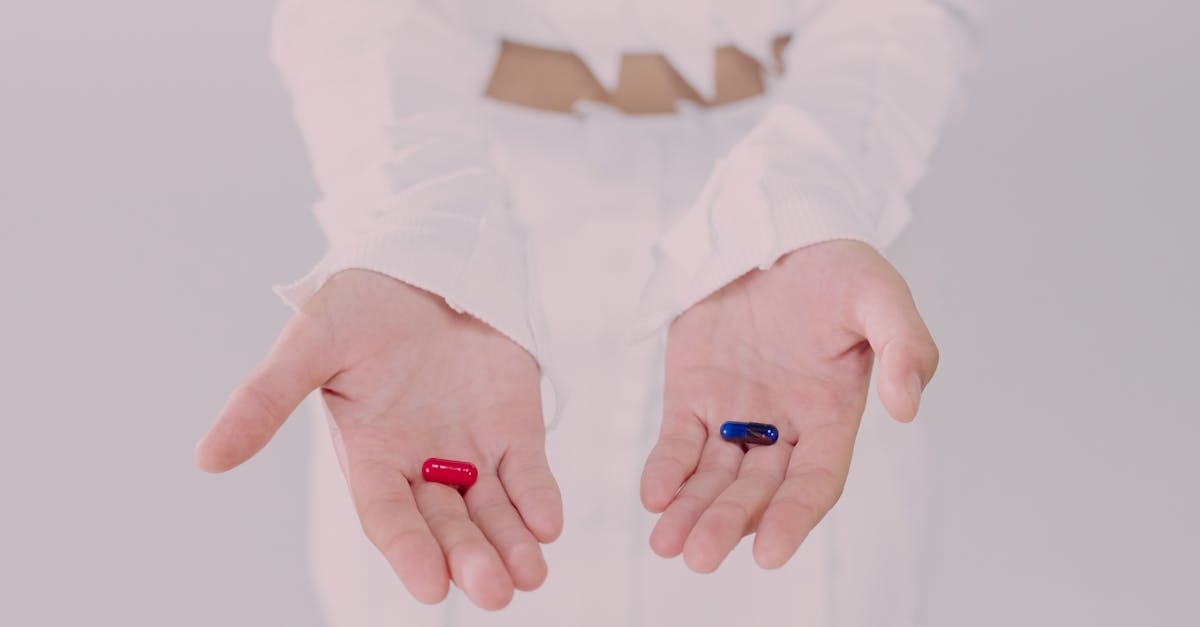 close up of hands holding red and blue pills symbolizing a choice conceptual studio shot