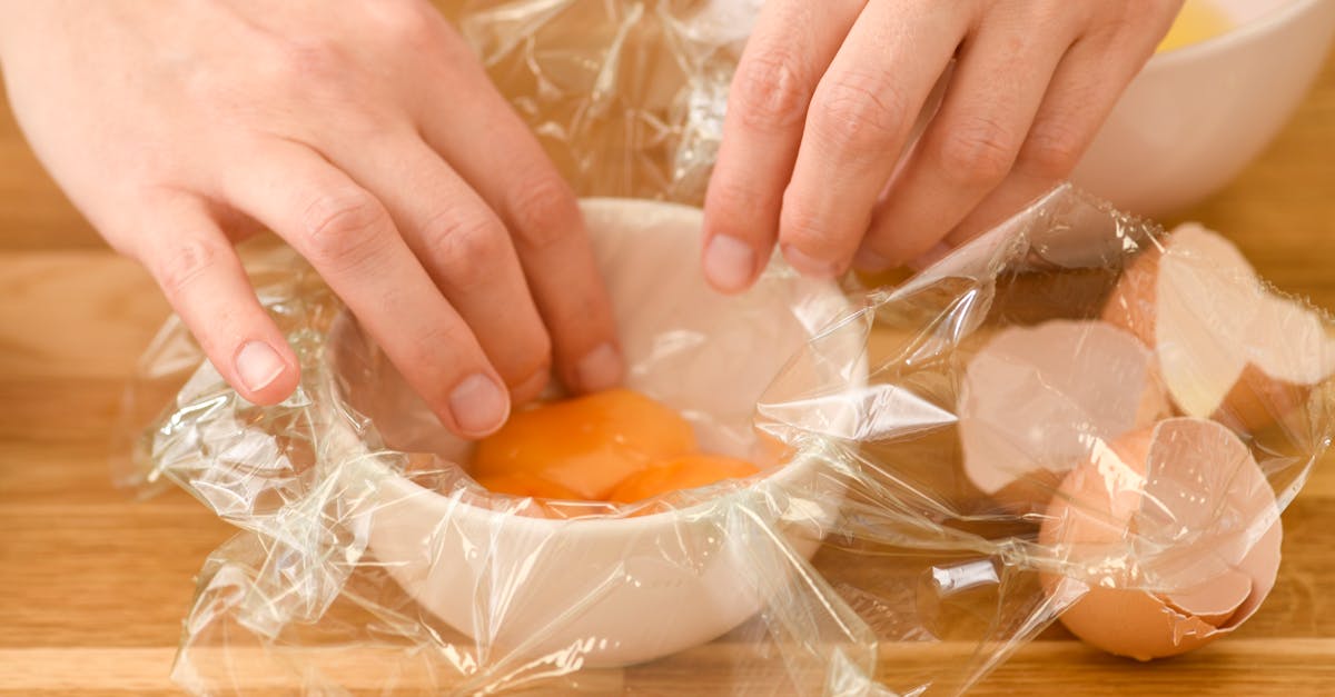 close up of hands preparing eggs with cling wrap for cooking