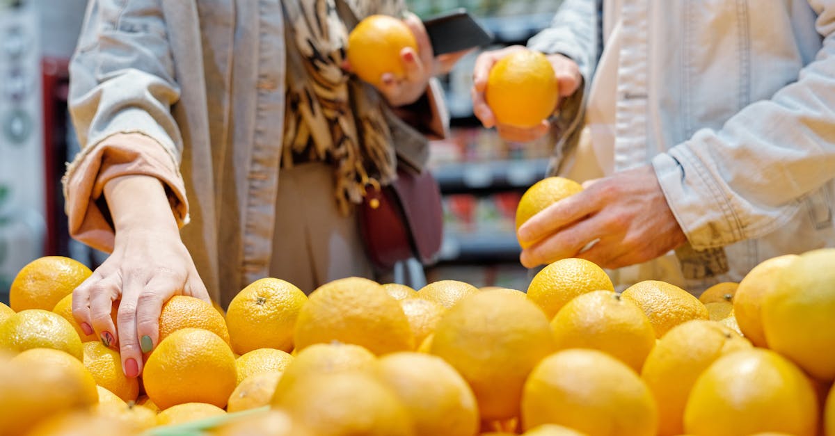 close up of hands selecting fresh oranges in a bustling market