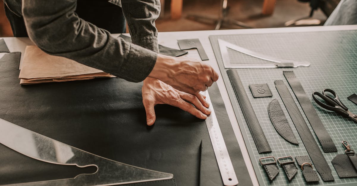 close up of hands working on leather crafting with tools in a workshop setting