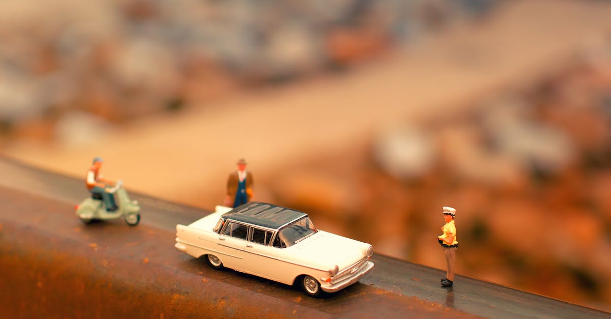 close up of miniature toy car scooter and figures on a rusty metal surface