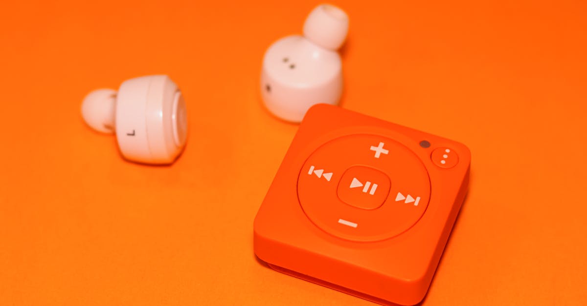 close up of wireless earphones and a compact music player on an orange background showcasing modern