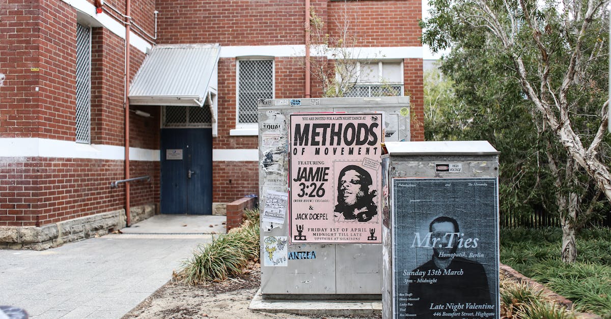 corner view of a brick building with urban posters and greenery