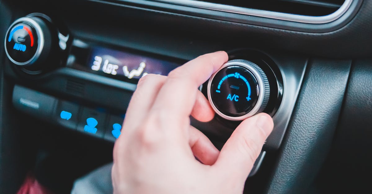 crop anonymous person regulating temperature in car using controller on panel while sitting in car