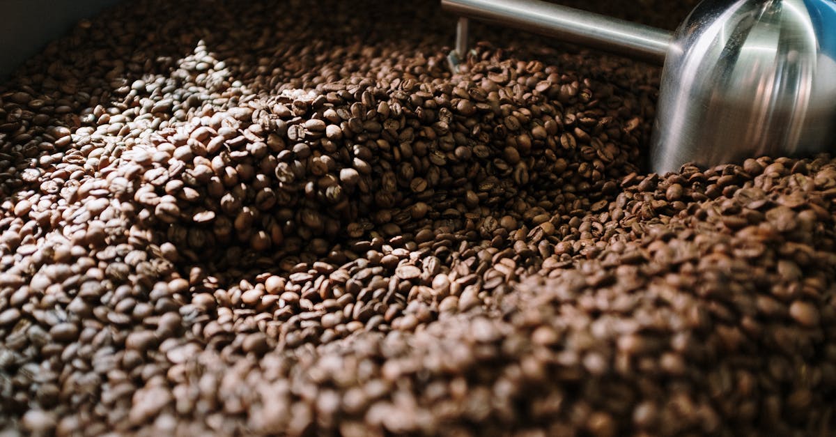 detailed view of brown coffee beans being roasted in a steel machine capturing the industrial proce