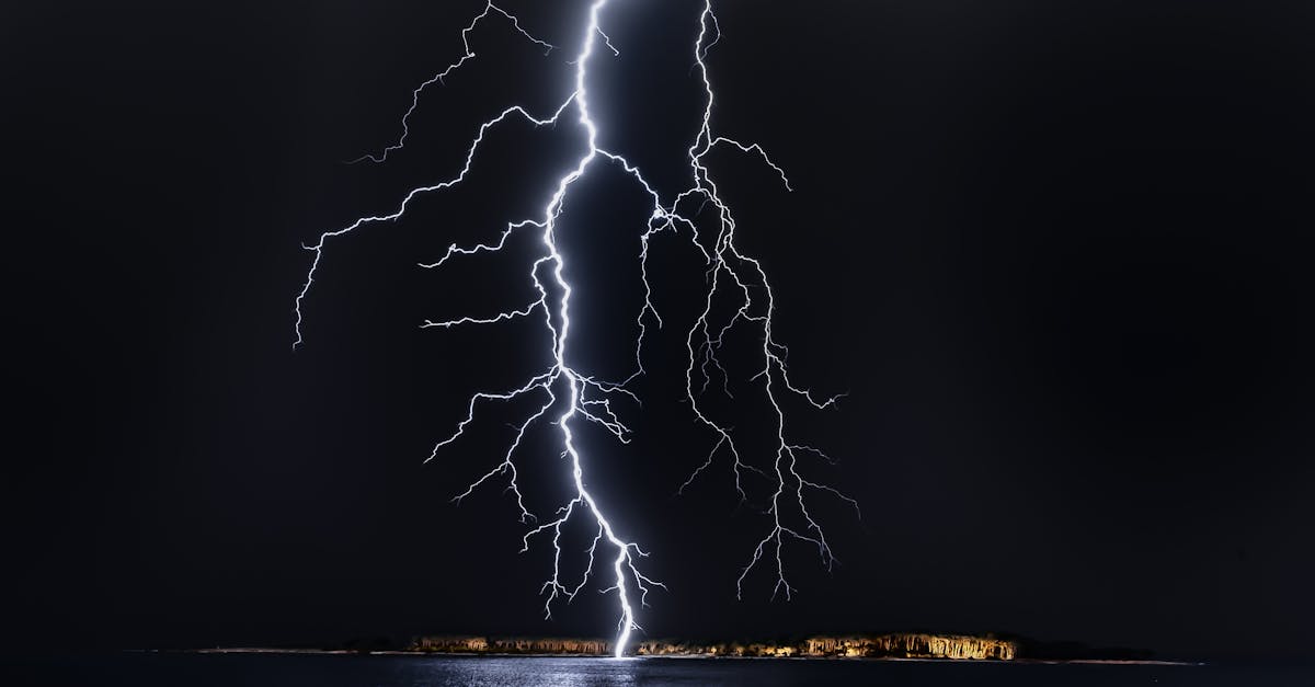 dramatic lightning bolt over the ocean at night illuminating the coastal landscape