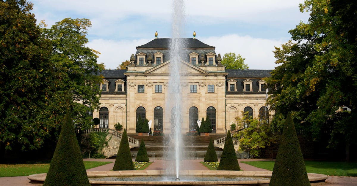 elegant historic mansion facade with central fountain surrounded by lush gardens offering a glimpse