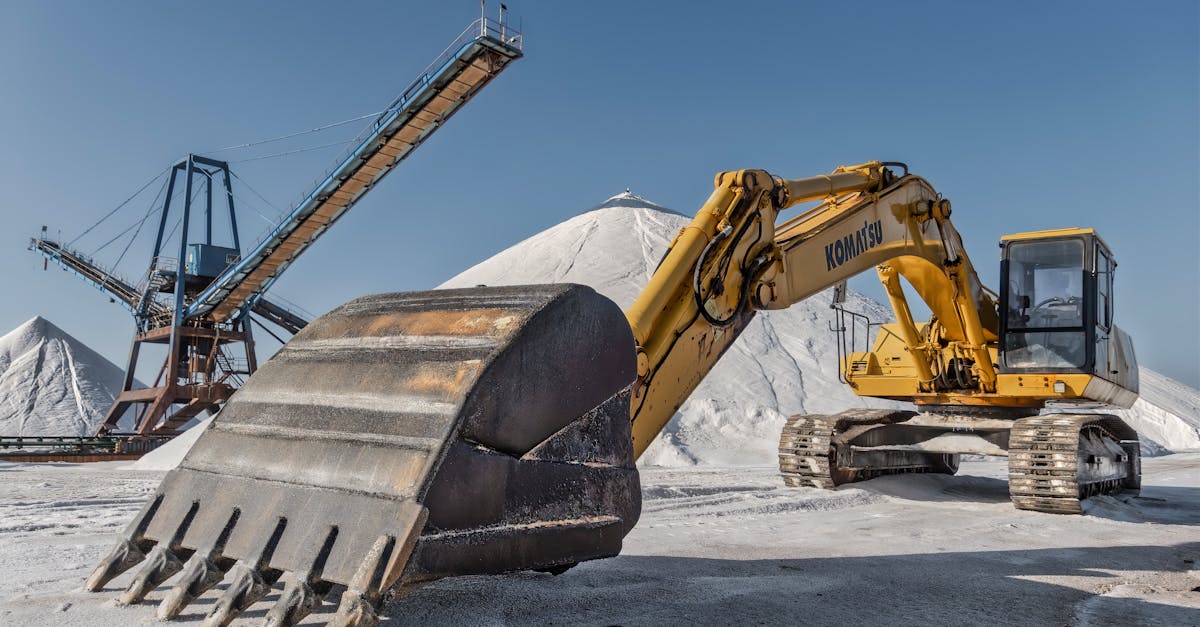 excavator and conveyor system in a snowy quarry under clear skies