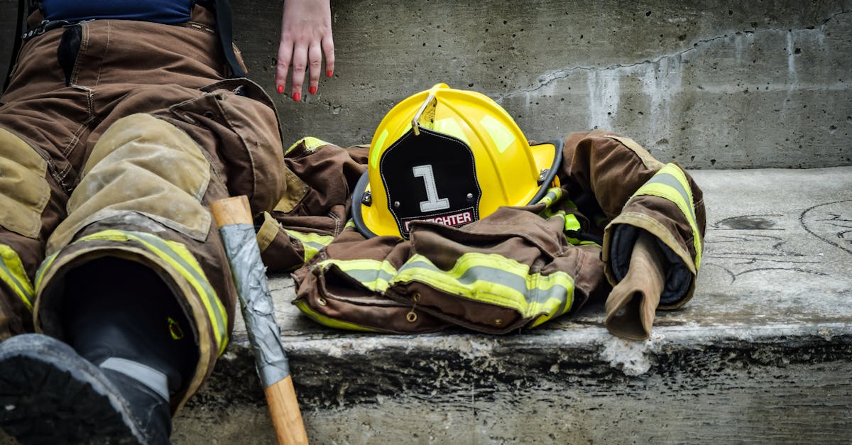 firewoman taking a break on concrete steps with gear and helmet nearby