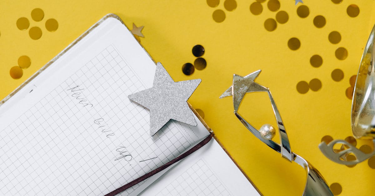 flat lay of a notebook with motivational text trophy and star confetti on a yellow background