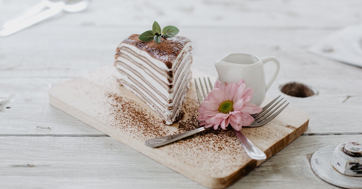 from above of appetizing piece of cake decorated chocolate powder and mint leaves served near cerami